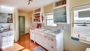 A kitchen with white cabinets, a double sink, and a window with a view of a snowy landscape. - Charming Farmington Home ~ 16 Mi to Aztec Ruins! (Farmington)
