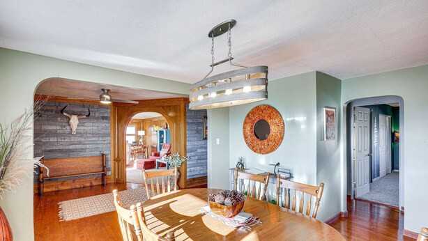 A dining area with a wooden table, chairs, and a ceiling light fixture. - Charming Farmington Home ~ 16 Mi to Aztec Ruins! (Farmington)