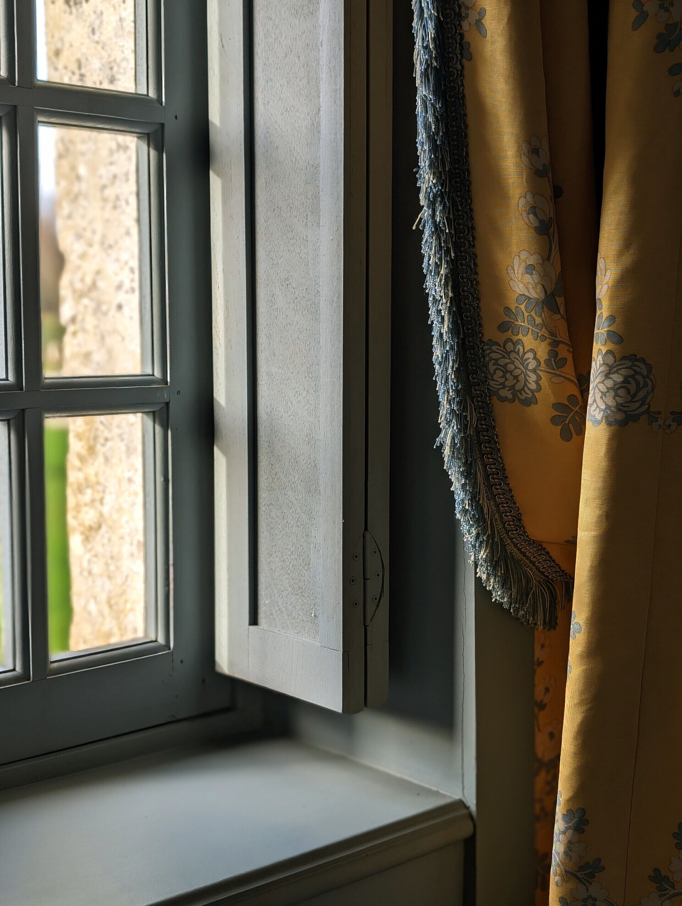 A window with a view of a stone wall outside.