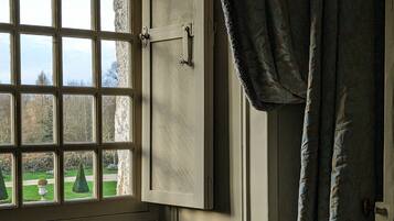 Una habitación con ventana, una silla y una cortina.