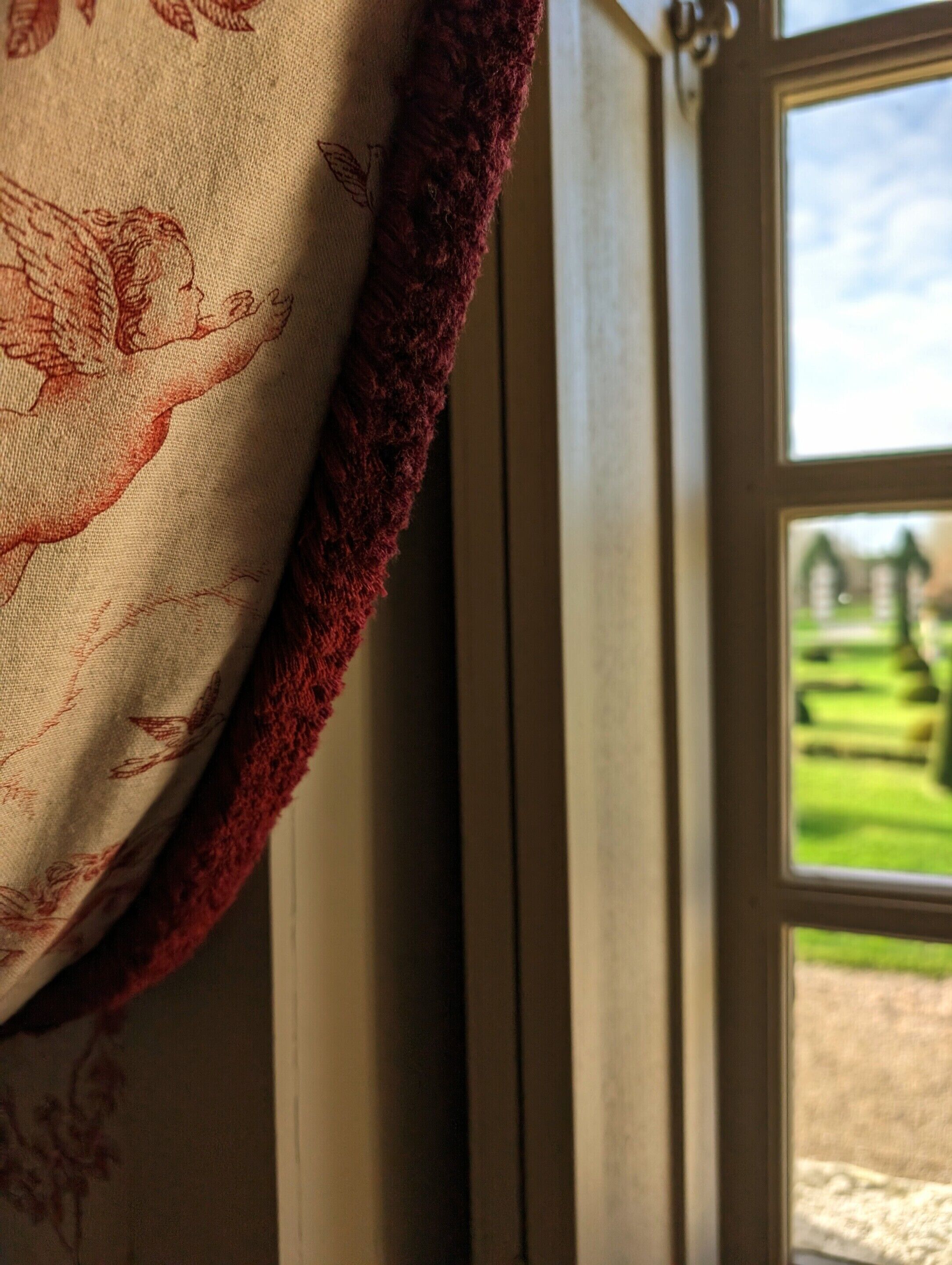 Una ventana con vistas a un paisaje verde y un edificio a lo lejos.
