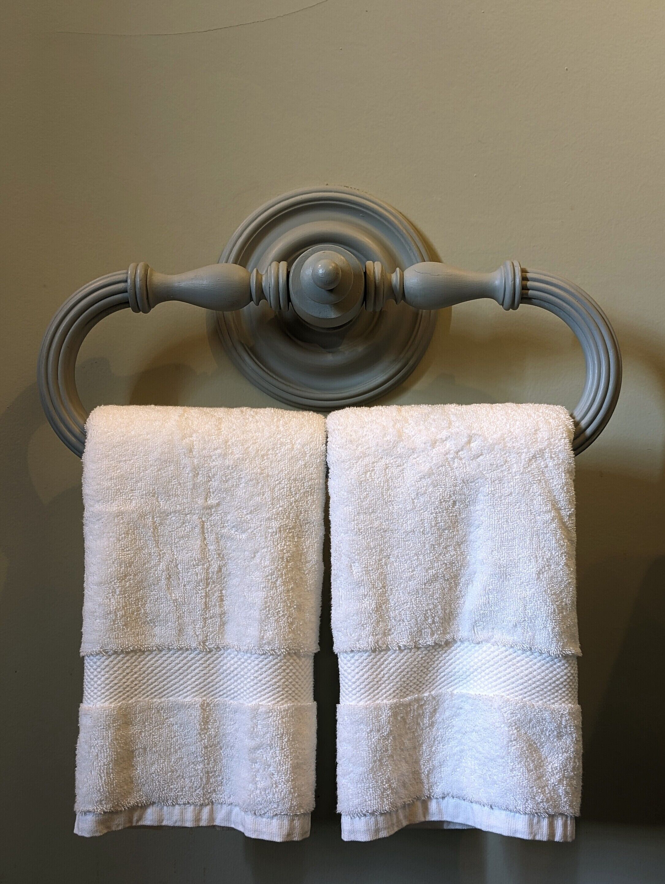 A towel rack with two white towels hanging.