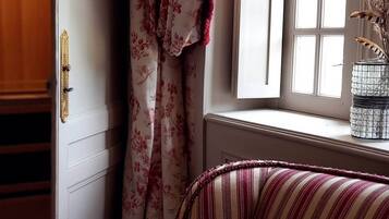Een kamer met een raam, een deur met een messing knop, en een gestreept kussen op een bed.
