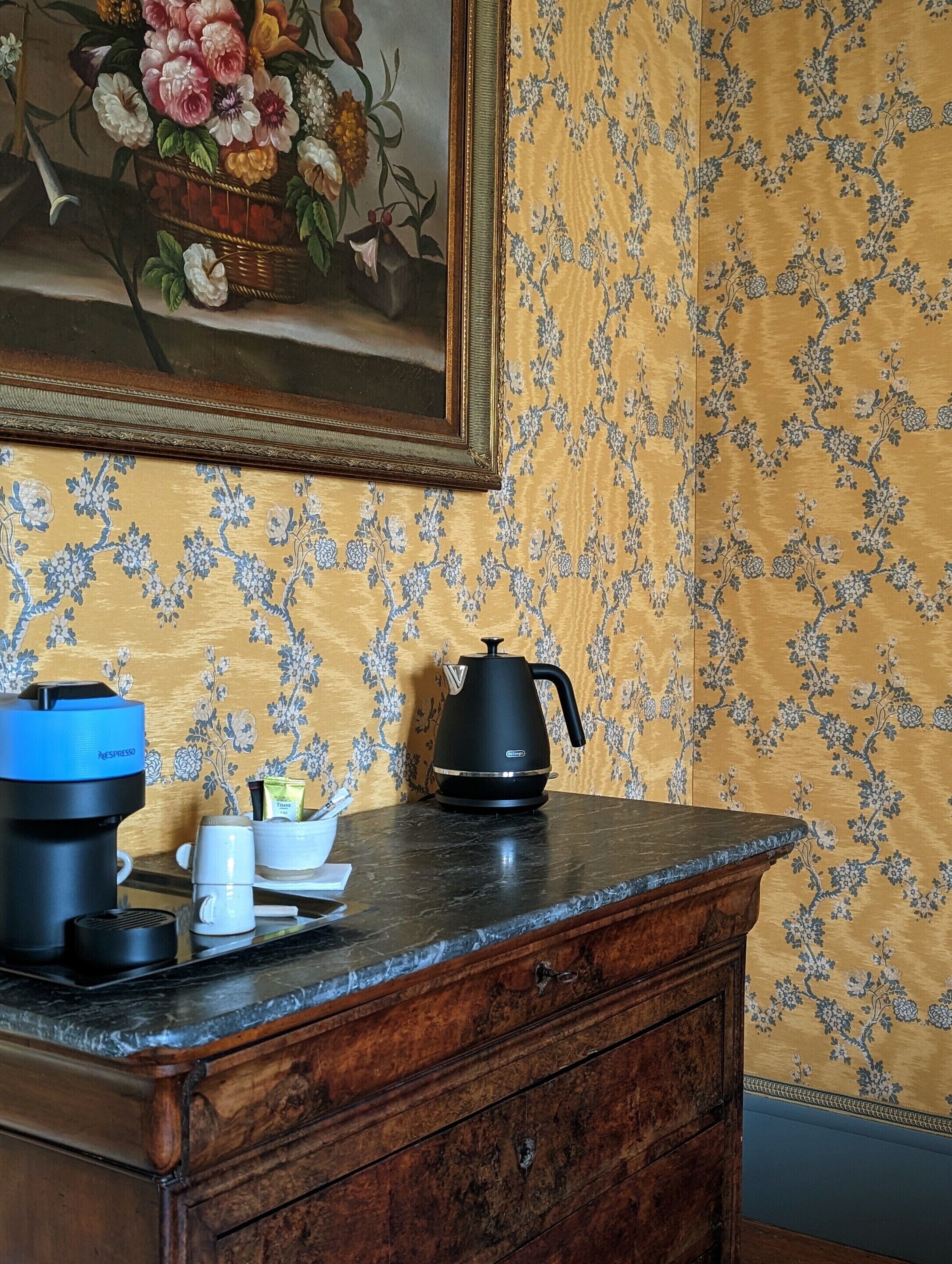 A kitchen counter with a coffee maker, a kettle, and a mug.