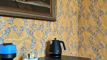 A kitchen counter with a coffee maker, a kettle, and a mug.