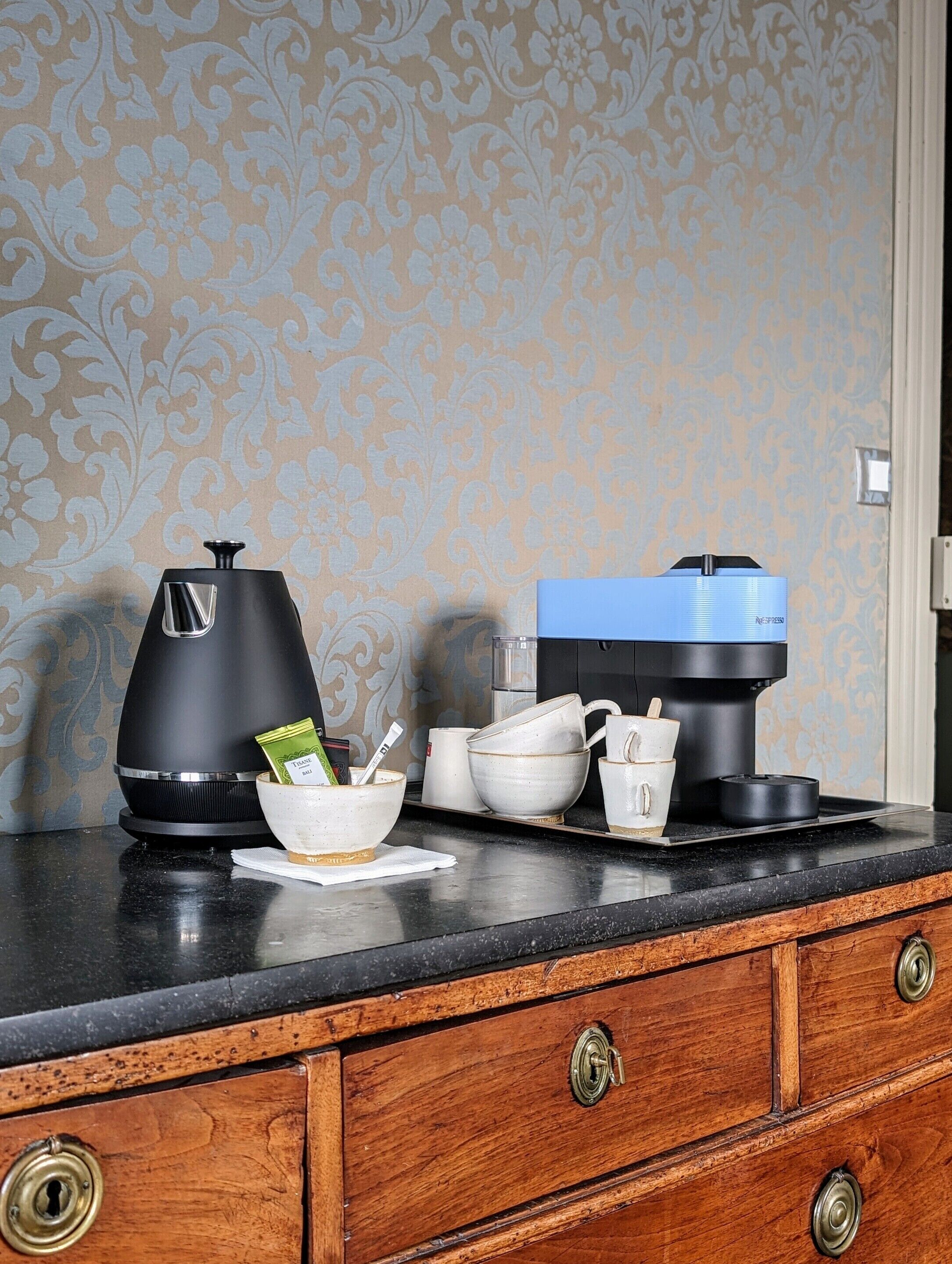 A kitchen counter with two coffee makers, a bowl, and a mug.