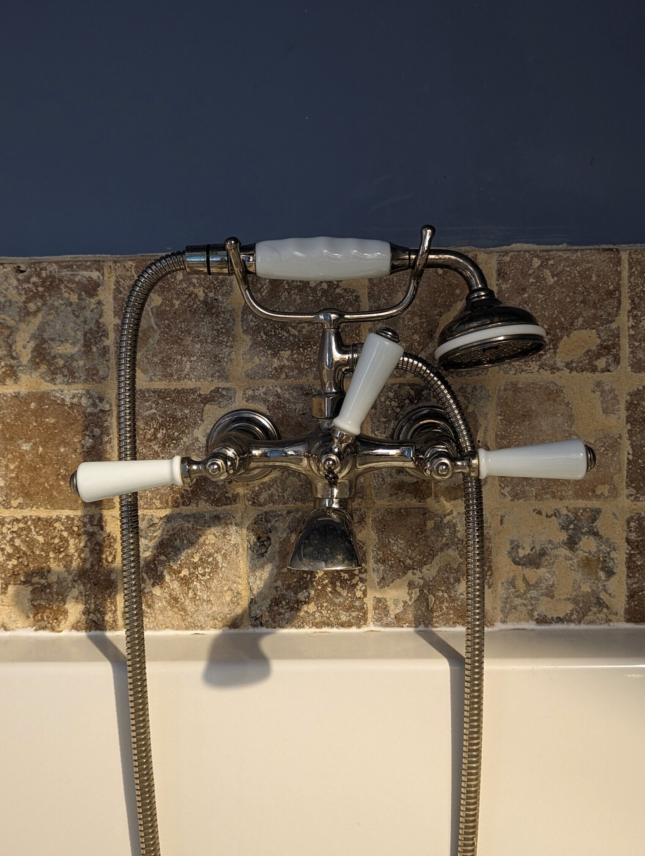 Un baño con bañera, ducha y grifo con manguera.