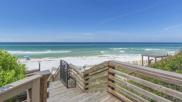 Una escalera de madera que lleva a una playa con vista despejada al océano.