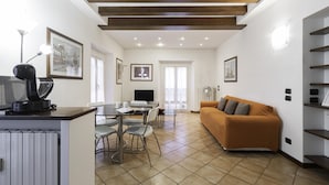 A modern living room with a sofa, a dining table with chairs, a coffee machine, and a TV. - Italianway Easy - Tadino 13 B (Milan)