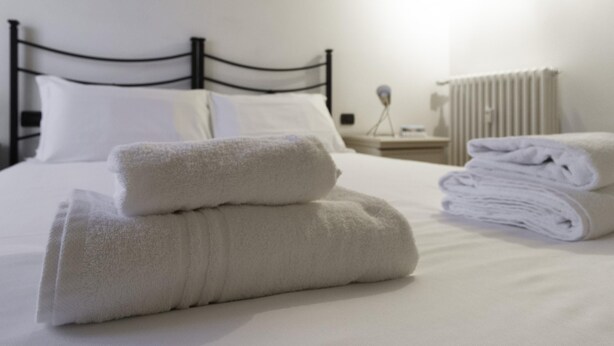 A neatly made bed with white linens and folded towels. - Italianway Easy - Tadino 13 B (Milan)