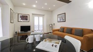 A modern living room with a glass dining table, a sofa, a TV, and framed pictures on the walls. - Italianway Easy - Tadino 13 B (Milan)