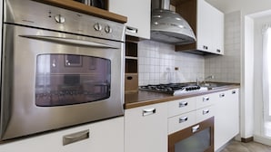 A modern kitchen with a stainless steel oven, a gas stove, white cabinets, and a wooden countertop. - Italianway Easy - Tadino 13 B (Milan)