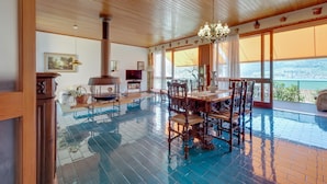 A spacious room with a large wooden ceiling, a dining area with ornate chairs, a fireplace, and a view of the outdoors. - Villa Olivella in Sale Marasino (Sale Marasino)