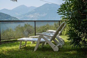 Vista de un paisaje montañoso con una zona de piscina que incluye dos sillones blancos y una mesita.