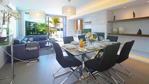 Een moderne eethoek met een glazen tafel, zwarte stoelen en uitzicht op de omgeving.