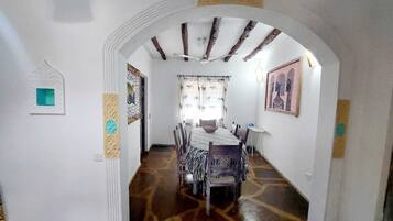 A dining area with a table set for four, a ceiling fan, and a patterned floor.
