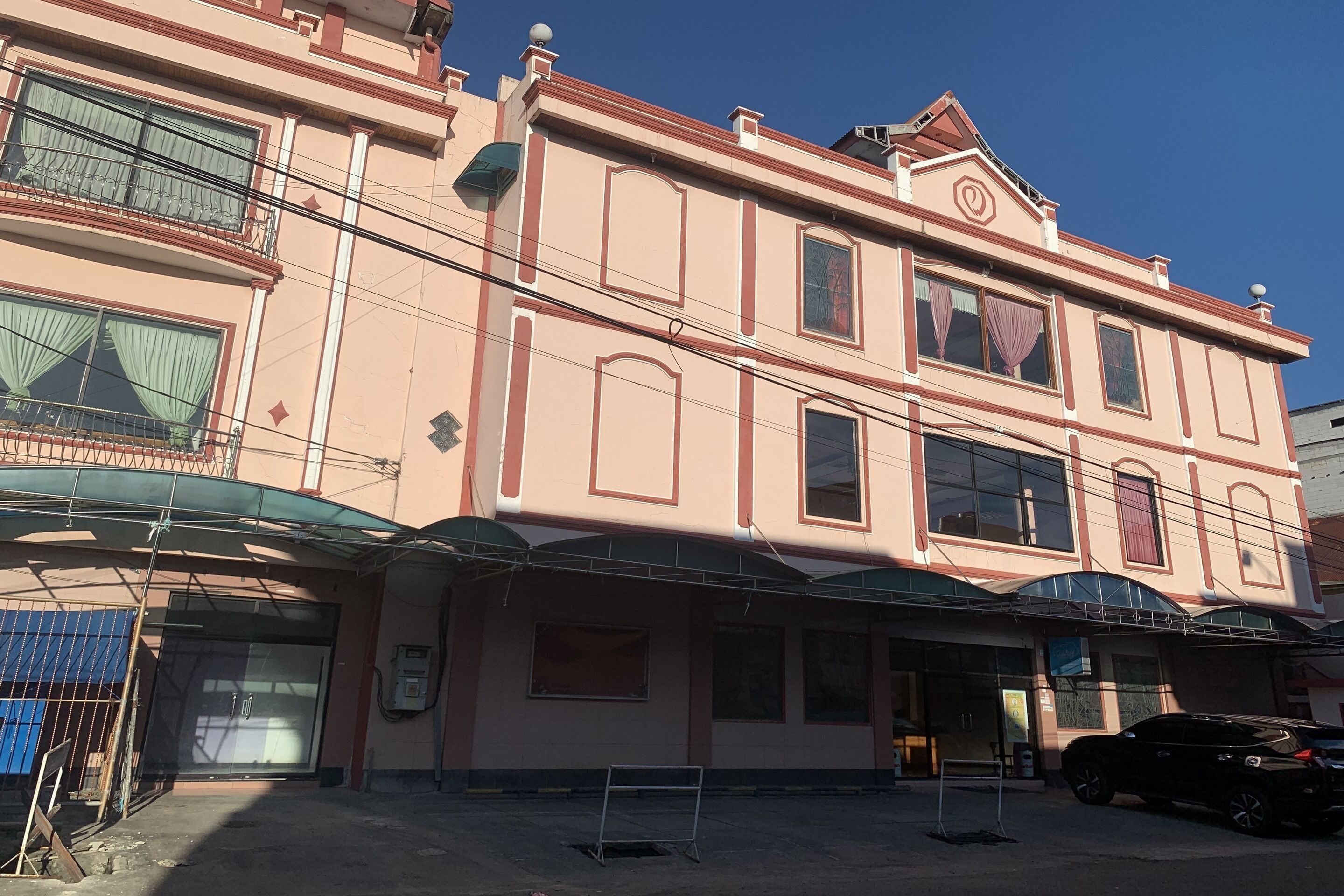 A multi-story building with a flat facade, large windows, and a covered entrance area.