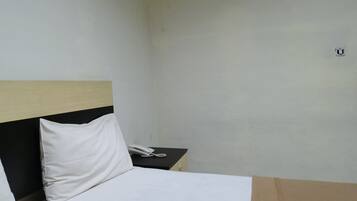 Quarto de hotel com uma cama, mesa de cabeceira e telefone.