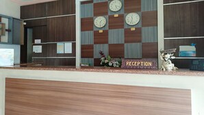 Un'area reception con un motivo a scacchi sulla parete, diverse orologi, una scrivania e un cartello di benvenuto.