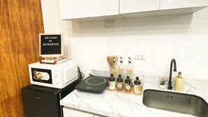A modern kitchen with white cabinets, a built-in microwave, a coffee machine, a sink, and a 'Welcome to Havenward' sign. - Studio bedroom in Circulo Verde near Eastwood Quezon city. Pet-Friendly! (Quezon City)