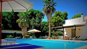 A swimming pool with lounge chairs and umbrellas, surrounded by palm trees and greenery. - Villa Virginia: private pool, walk 3min for beach and 30min for Paestum temples. (Licinella-Torre di Paestum)