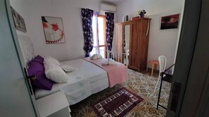 Una camera da letto con un letto, un armadio, una finestra con tende e un tappeto decorato.