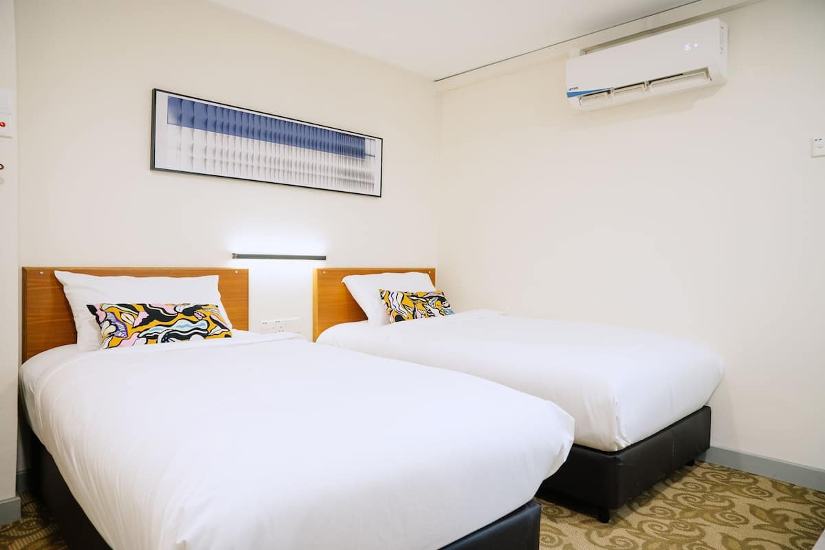 A hotel room with two beds, a large framed artwork on the wall, and an air conditioning unit.
