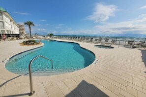 A pool area with a curved design, a lifeguard stand, and a view of the ocean.