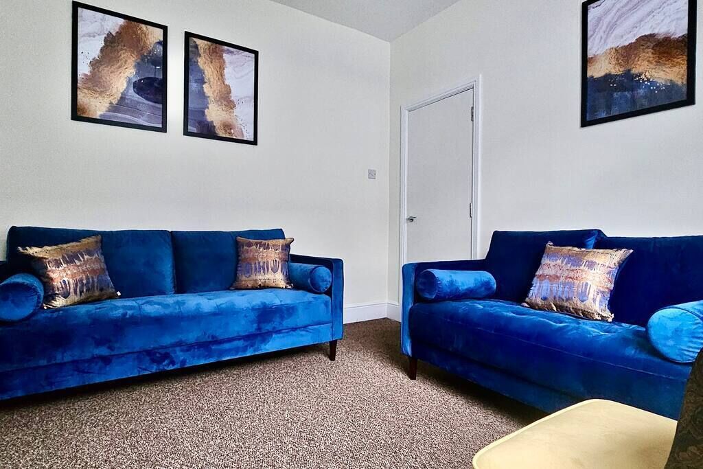 A room with two blue sofas, a door, and two abstract paintings on the wall.