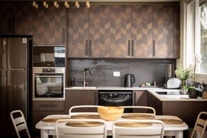A modern kitchen with a herringbone-patterned backsplash, built-in appliances, and a dining area with woven placemats. - MAMAD - Seabreeze Serenity Haven by Sea N' Rent (Tel Aviv)