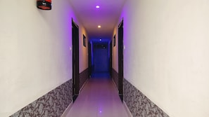 Un pasillo con paredes con diseño y suelo de baldosas que conduce a una puerta con motivos geométricos.