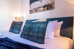A bed with a dark headboard, white bedding, and patterned pillows. - Sleek 3-BR Apartment, Central Hartlepool (Hartlepool)
