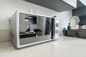 A compact, modern kitchen with a built-in microwave, a sink, and a countertop. - Stylish 3-BR Apartment in Hartlepool (Hartlepool)