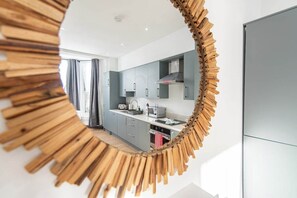 A modern kitchen with grey cabinets, a microwave, and a stainless steel range hood. - Stylish 3-BR Apartment in Hartlepool (Hartlepool)