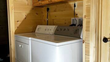 A compact laundry room with wooden walls and cabinets, a washing machine, and a dryer.