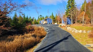 A rural road leading to a small cabin with a blue exterior and a red star on the roof.