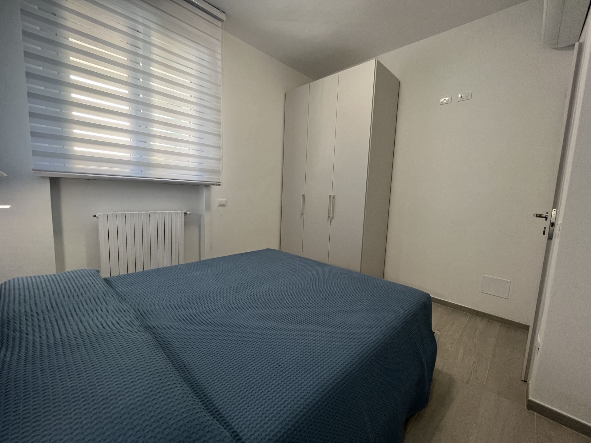 A bedroom with a bed, a wardrobe, and a radiator.