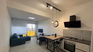 Una cucina moderna con angolo ristoro, televisore e divano.