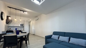 Un soggiorno moderno con un divano blu e una zona pranzo con tavolo e sedie.