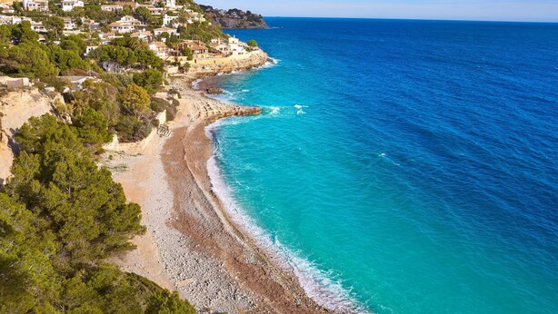 A coastal town with a beach, houses on a hillside, and the sea.