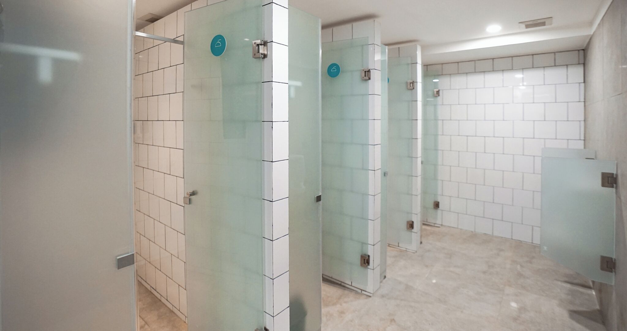 Ein modernes Badezimmer mit Glastrennwänden, weißen Fliesenwänden und einem gefliesten Boden.
