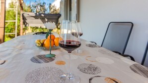 A table with a glass of red wine, a bowl of fruit, and a chair. - Holiday home Loncar (Vir)