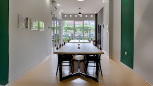 A modern conference room with a long table, chairs, and pendant lighting. - HUBS Hostel Yogyakarta (Yogyakarta)