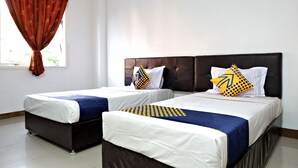 Dos camas individuales con cabeceras, ropa de cama blanca y almohadas decorativas azules y amarillas.