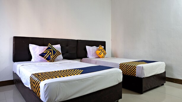 Habitación de hotel con dos camas, cada una con cabecero oscuro y ropa de cama blanca.