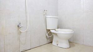 Un baño con inodoro, ducha y paredes de azulejos.