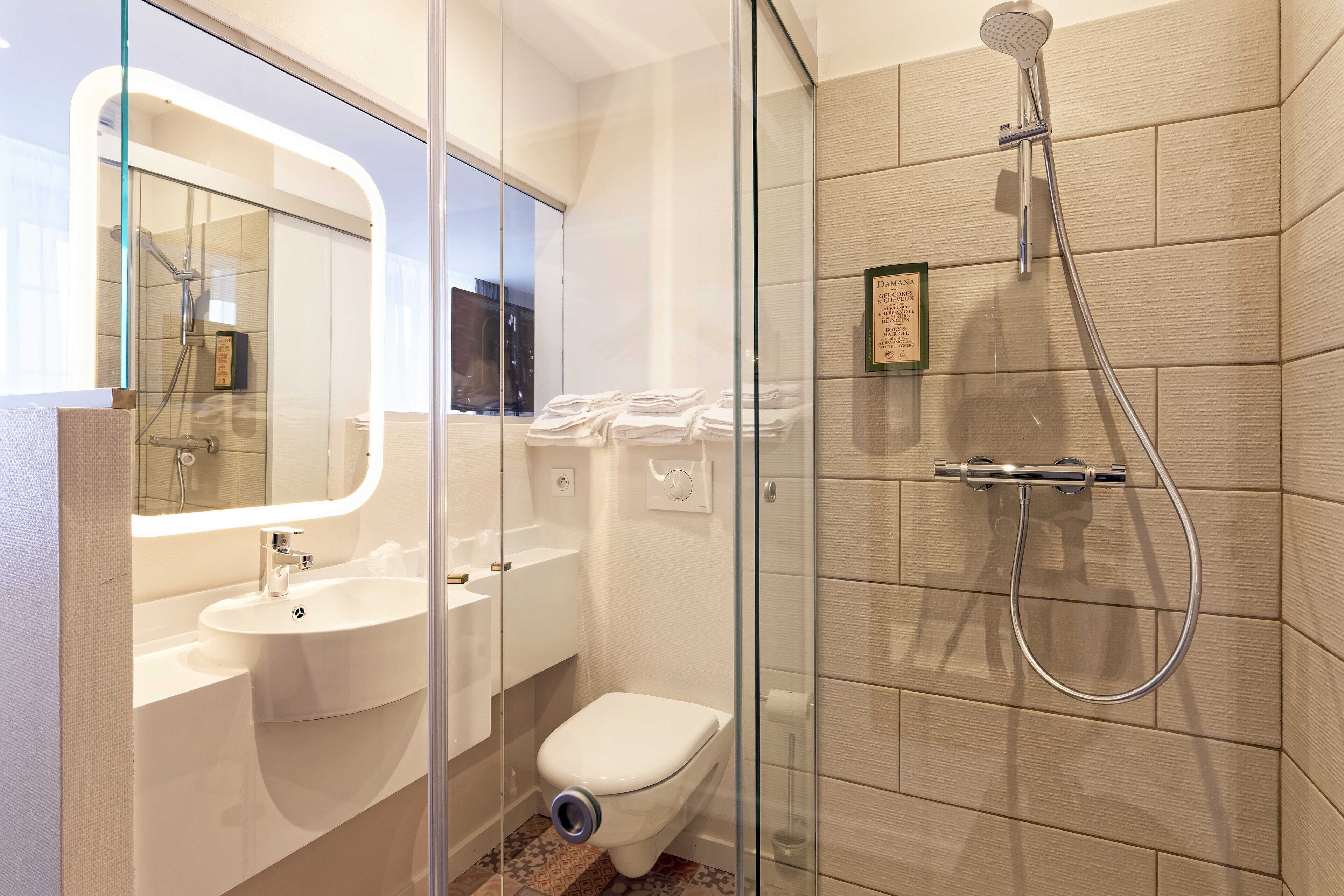 A modern bathroom with a glass-enclosed shower, a white sink, and a toilet.