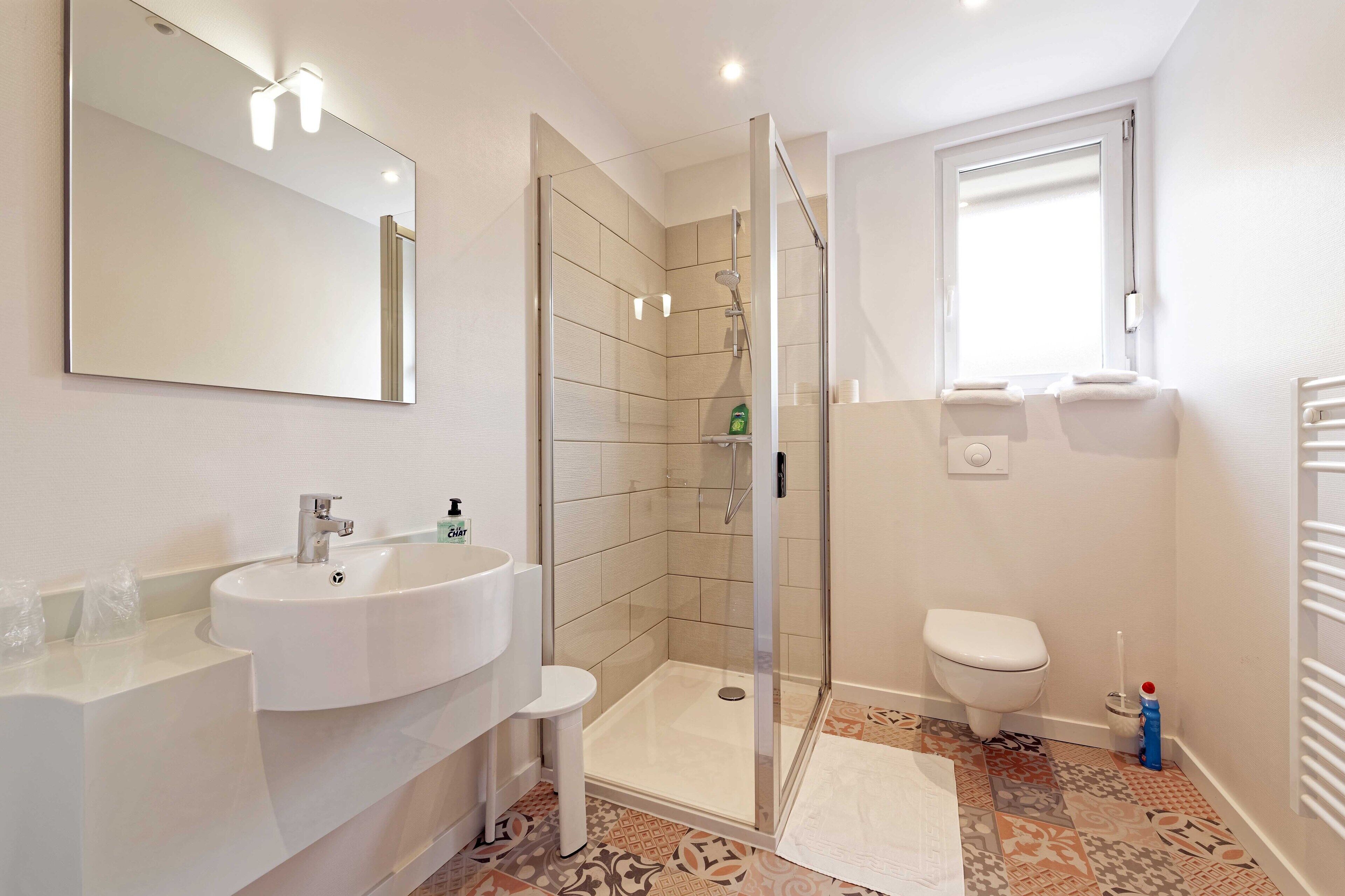 Ein modernes Badezimmer mit Waschbecken, Duschkabine, Toilette und großem Spiegel.