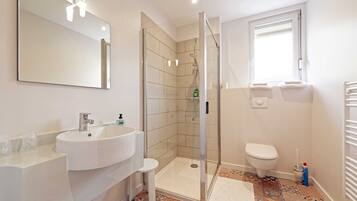 Ein modernes Badezimmer mit Waschbecken, Duschkabine, Toilette und großem Spiegel.