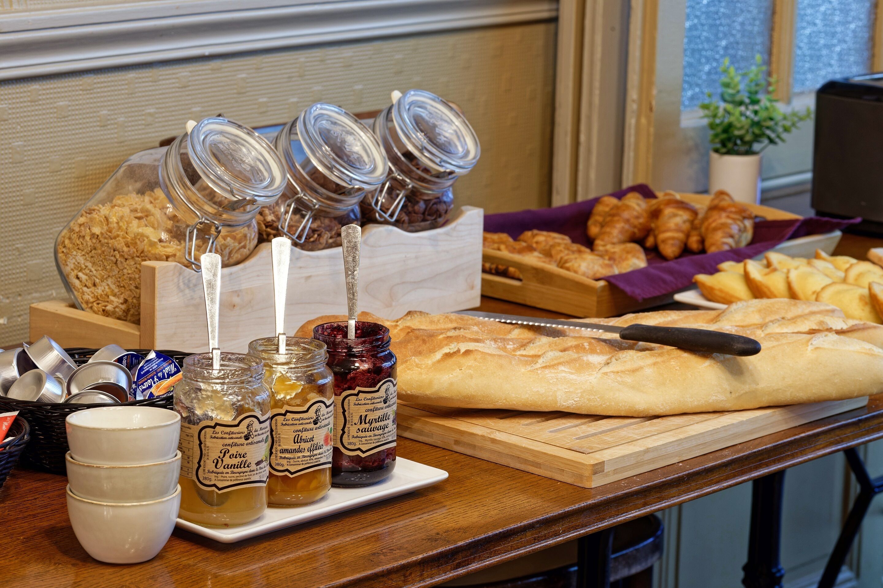 A breakfast spread with pastries, bread, and jars of jam.